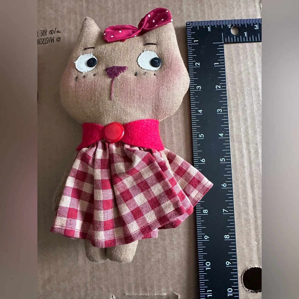 Handmade cloth cat doll in a red and white plaid dress.